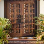 LK 649 solid wood double main door with carved floral rosettes on square panels and brass studs, by LK Doors and Interiors